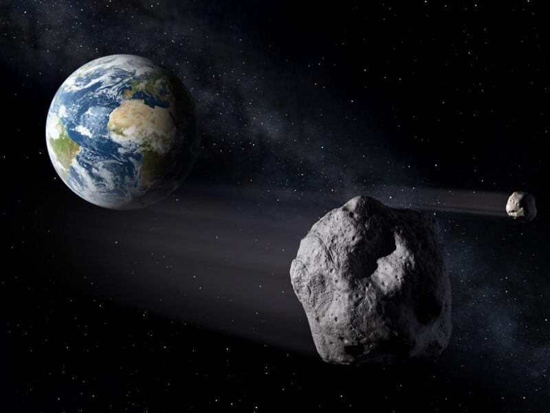 An asteroid portrayed to be passing in front of the blue-green Earth and the moon.