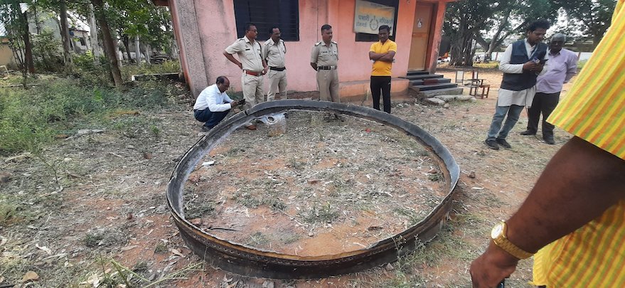 Photo of people standing next to a large metal ring that fell into rural western India April 2, along with a cylinder-like object believed to be parts of a Chinese rocket’s upper stage.
