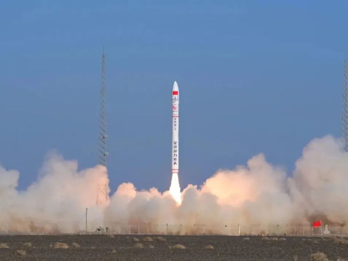 A white Ceres-1 rocket lifts off from Jiuquan amid a cloud of exhaust and sand, rising into a clear blue sky.