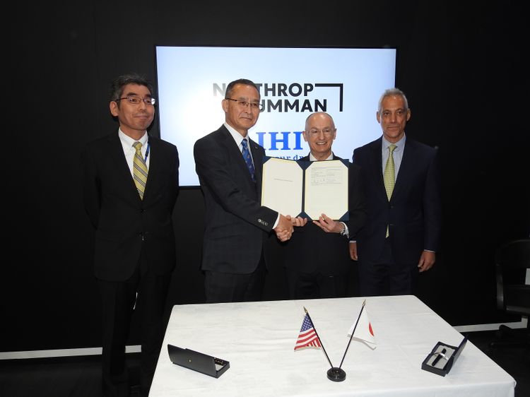 Two men hold up a document representing the space domain awareness agreement signed by IHI Corp. and Northrop Grumman.